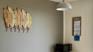 A dining area with a table, chairs, a decorative wall piece, a hanging light fixture, and a sign on the wall. - La Tranquille - House for 3 families (Saint-Denis-d'Oléron)