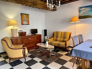 A living room with a checkered floor, a sofa, a dining table, and a chandelier. - Gîte Le Marigny in the heart of Morvan (Marigny-l'Église)
