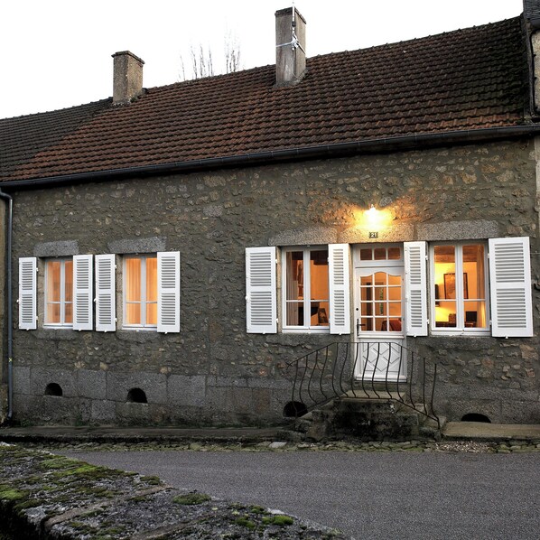 A stone building with a tiled roof, numbered 21, featuring white shutters on windows and a small porch area. - Gîte Le Marigny in the heart of Morvan (Marigny-l'Église)