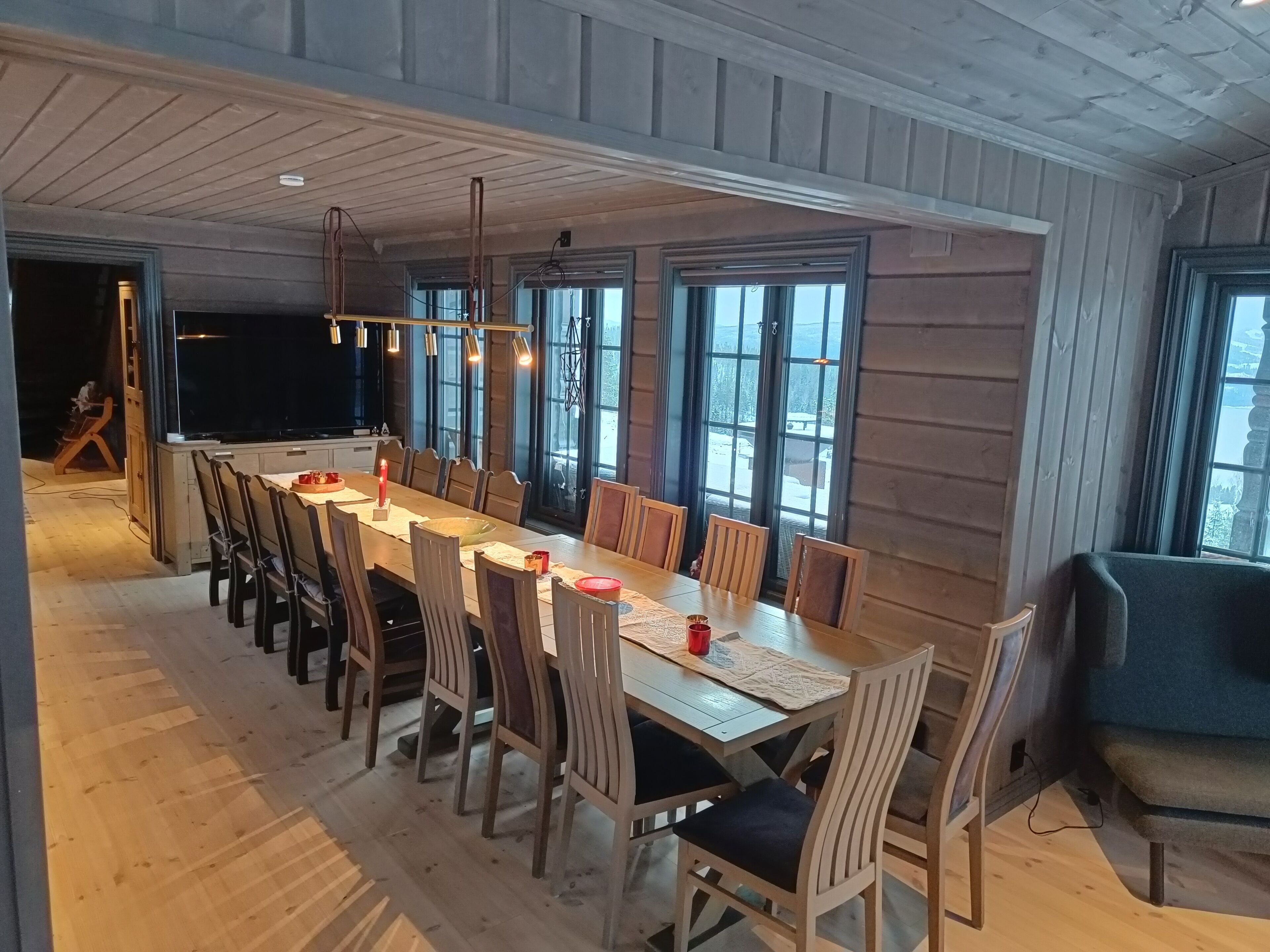 Un espace repas comprenant une longue table en bois, plusieurs chaises et un luminaire suspendu au design moderne.