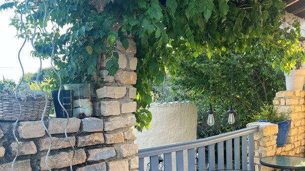 A stone wall with a metal railing, a glass table, and potted plants. - Pretty Provencal house in a medieval village (Bouchet)