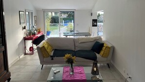 A modern living room with a sofa, a glass coffee table, and a dining area visible through a glass door. - Pretty Provencal house in a medieval village (Bouchet)