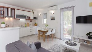 Et moderne køkken med lyse skabe, en mikroovn og et spiseområde med bord og stole.