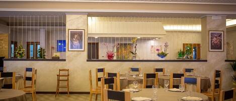 Un restaurante con mesas redondas, sillas y piso a cuadros.