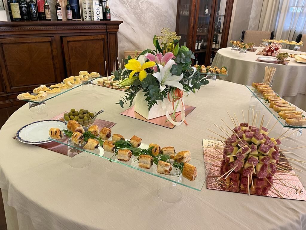 Une table de buffet proposant divers plats, notamment des pâtisseries, des sandwichs, et un centre de table agrémenté de fleurs.