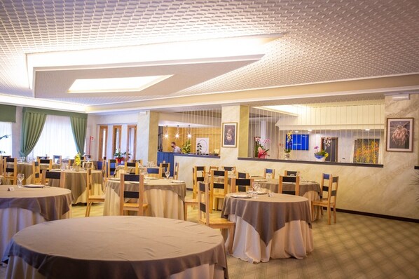 Un restaurant avec des tables rondes, des chaises et un coin bar.
