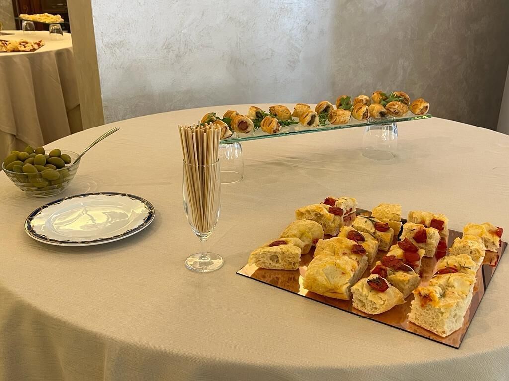 A buffet table with various food items, including pastries and a bowl of olives.