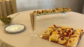 A buffet table with various food items, including pastries and a bowl of olives.
