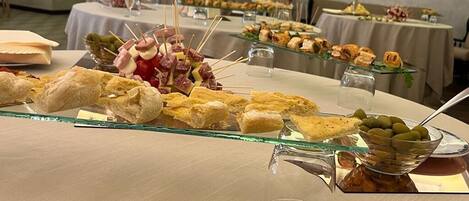 A buffet table with various food items including sandwiches, skewers, and olives.