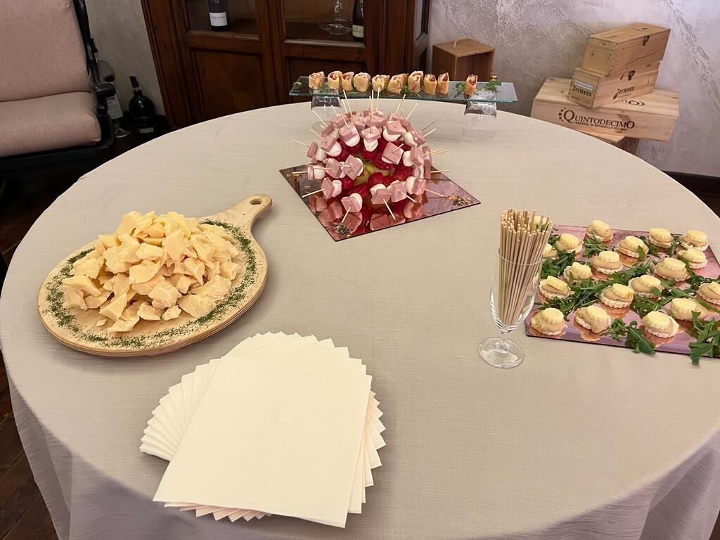A round table with various food items, including a plate of cheese, a dessert centerpiece, and a tray of sandwiches.