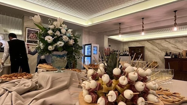 A buffet table with various food items, including skewers with meat and cheese, and a floral centerpiece. - Il Bivacco del Parco Sport Hotel & Residence (Taverna)