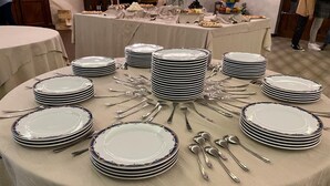 A round table set with multiple stacks of white plates and silverware, surrounded by a beige tablecloth. - Il Bivacco del Parco Sport Hotel & Residence (Taverna)