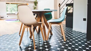 Un comedor moderno con una mesa redonda, cuatro sillas y un suelo de baldosas blanco y negro.