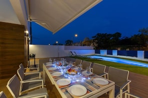 An outdoor dining area with a pool in the background.