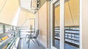 Ein Balkon mit Tisch und Stühlen, einem Blumentopf und Blick auf Gebäude.