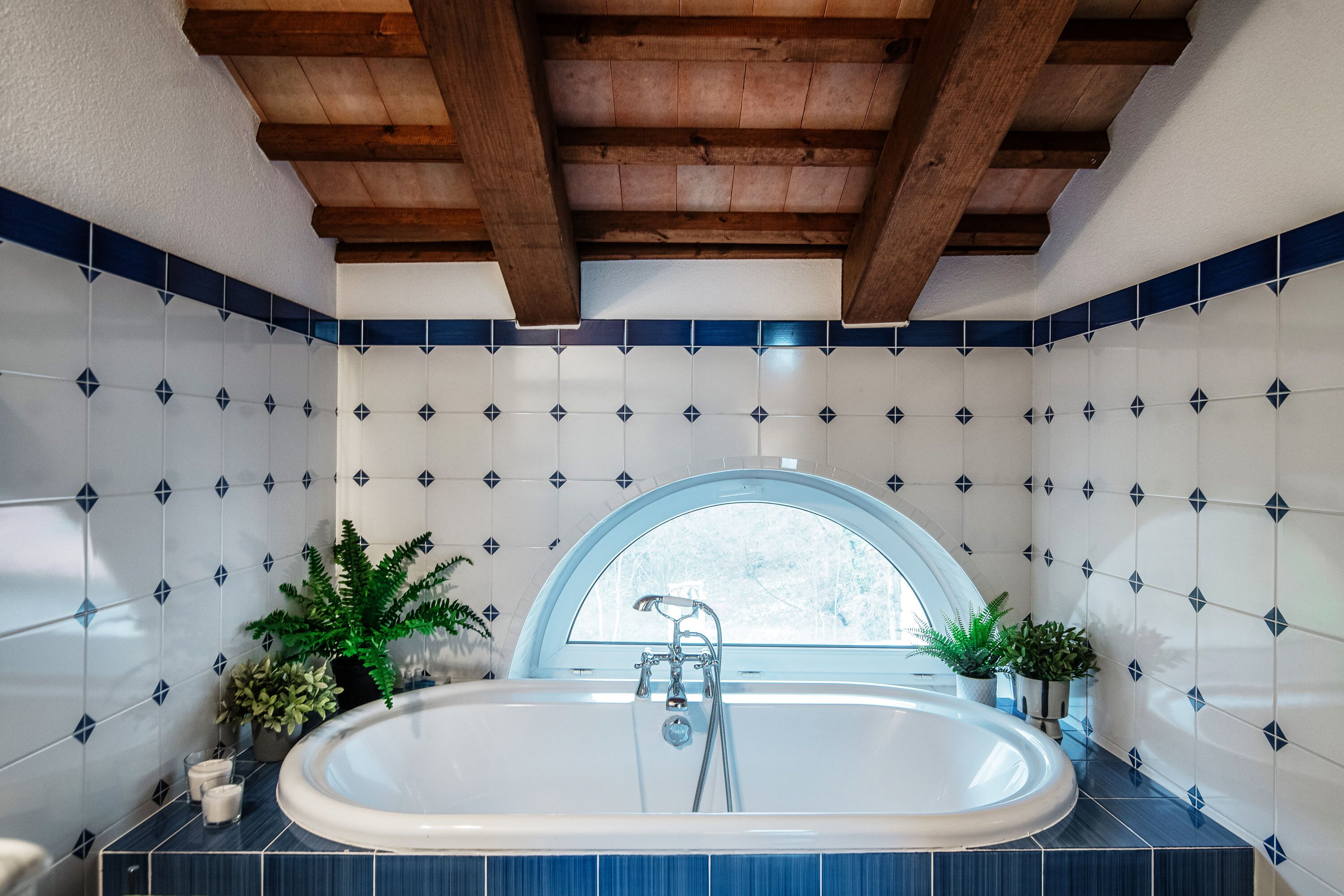 Ein Badezimmer mit einer freistehenden Badewanne, einem Fenster und dekorativen Fliesen.