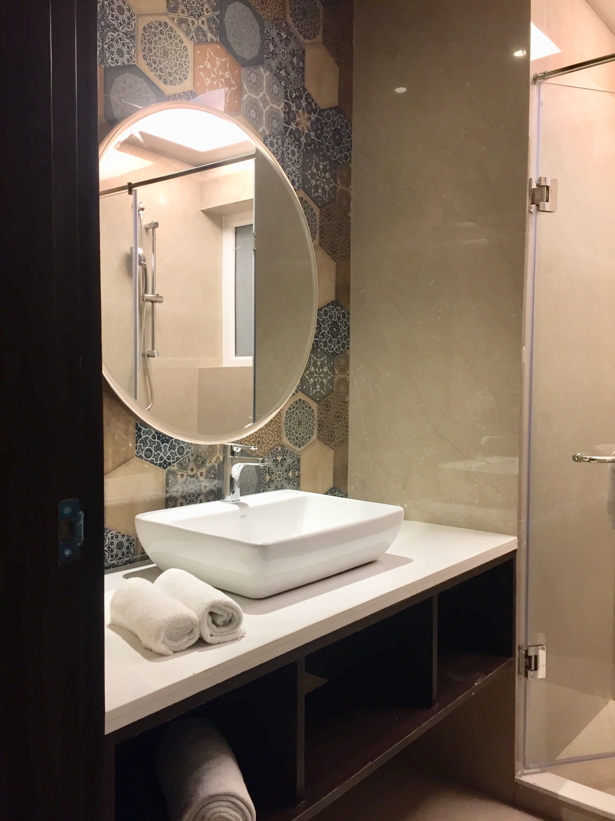 A bathroom with a white sink, a round mirror, and a shower.