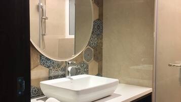 A bathroom with a white sink, a round mirror, and a shower.