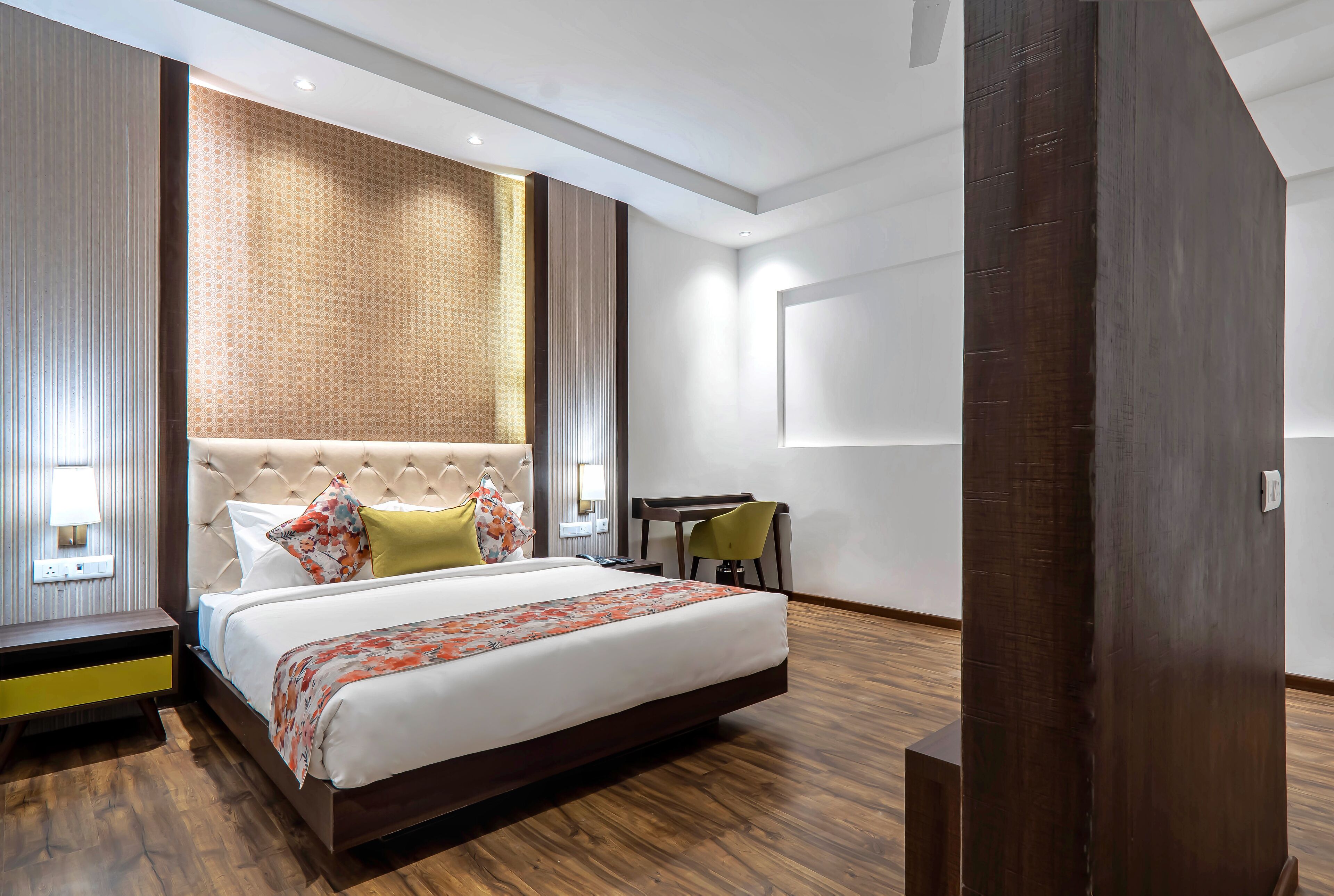 A modern hotel room with a large bed, a desk, and a chair.