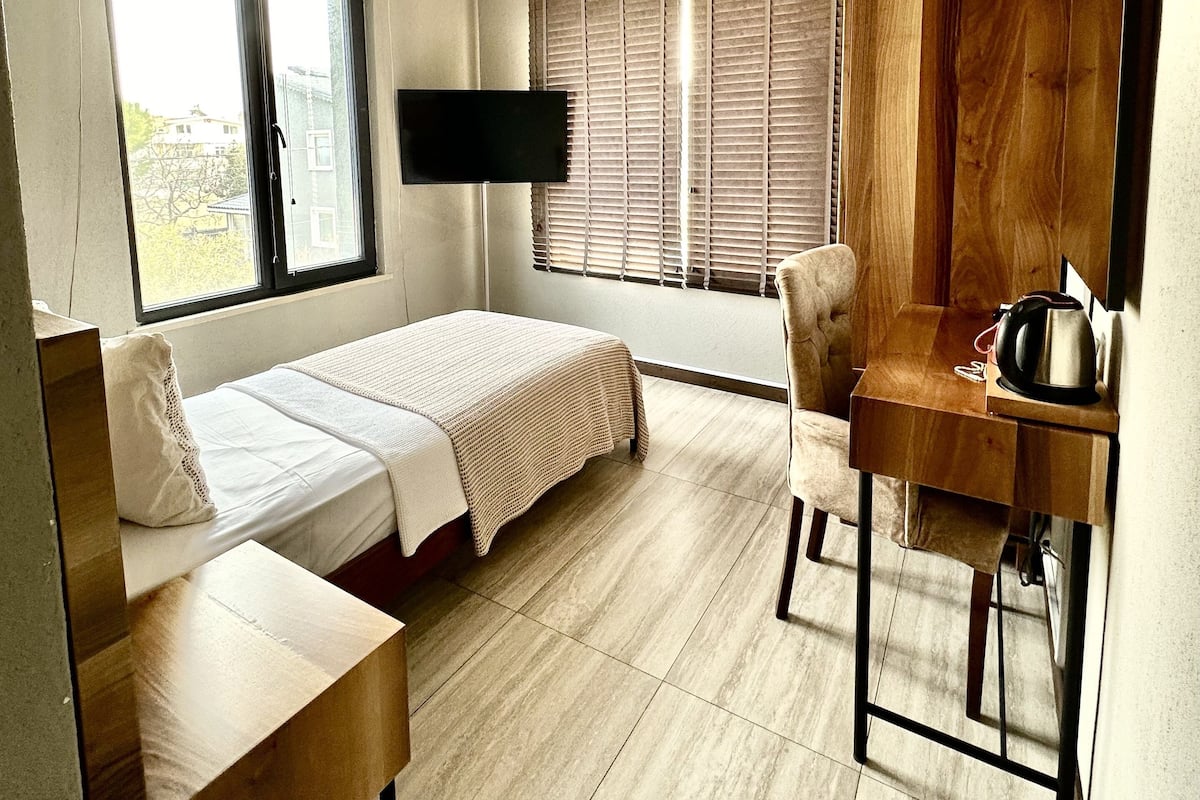 Une chambre à coucher moderne avec un lit, un bureau, une chaise et un téléviseur.