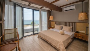 A hotel room with a large bed, a chair, a nightstand, and a view of the sea through a sliding door. - Villa Siesta Hotel Istanbul Airport (Arnavutköy)