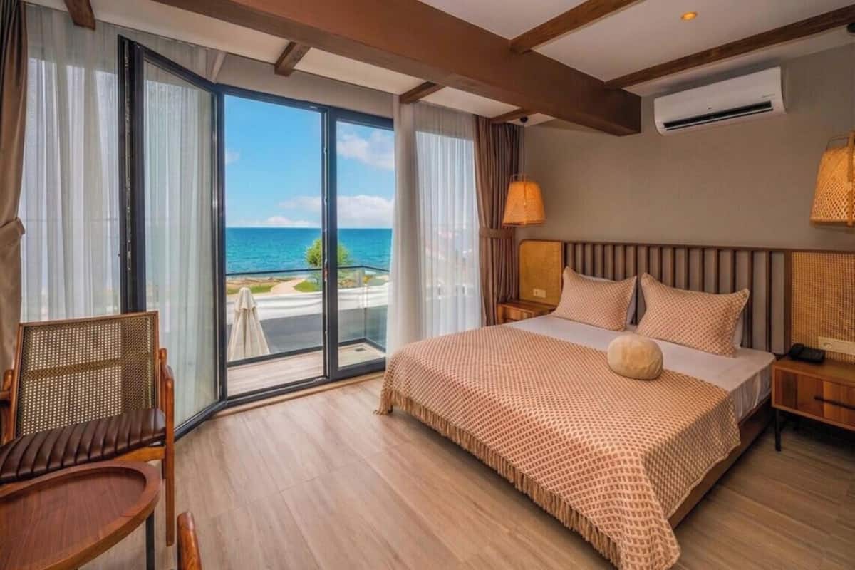 Une chambre d’hôtel avec un grand lit, une chaise, une table de chevet et une vue sur l’océan.