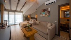 A modern hotel room with a large bed, a sofa, a wooden coffee table, and a dining area with a bowl. - Villa Siesta Hotel Istanbul Airport (Arnavutköy)