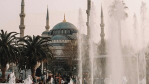 A fountain with multiple water jets in front of a mosque with a dome and minarets. - Villa Siesta Hotel Istanbul Airport (Arnavutköy)