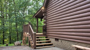 A wooden cabin with a porch and steps leading to a door. - Pisgah Pines | Cozy Log Cabin w/ Hot Tub & Fire Pit Near Asheville Airport (Arden)