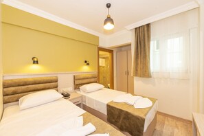 Une chambre d’hôtel avec deux lits, une table de chevet avec une lampe, une armoire et une fenêtre avec des rideaux.