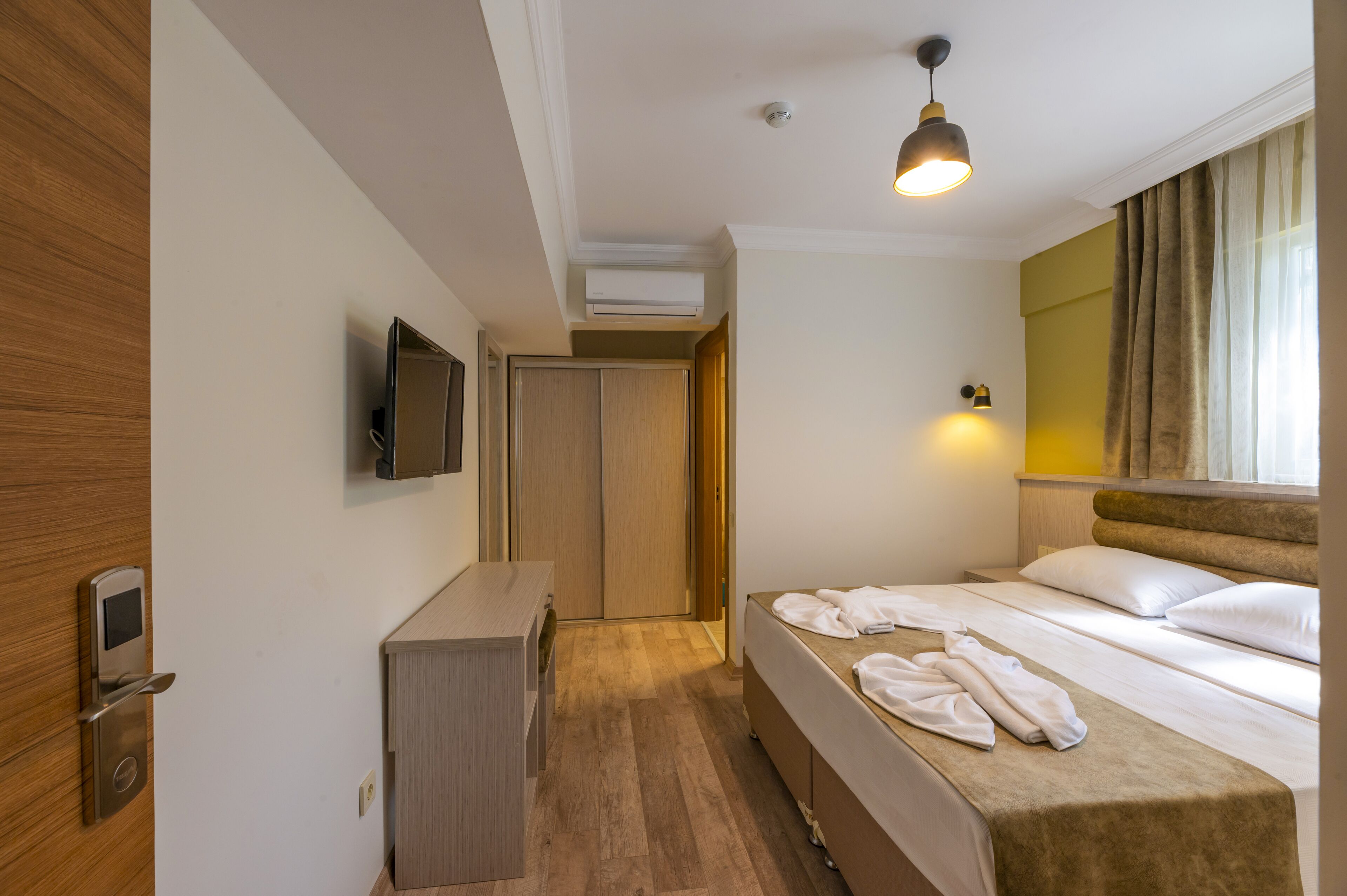 Una habitación de hotel con una cama, un escritorio, un televisor y un armario.
