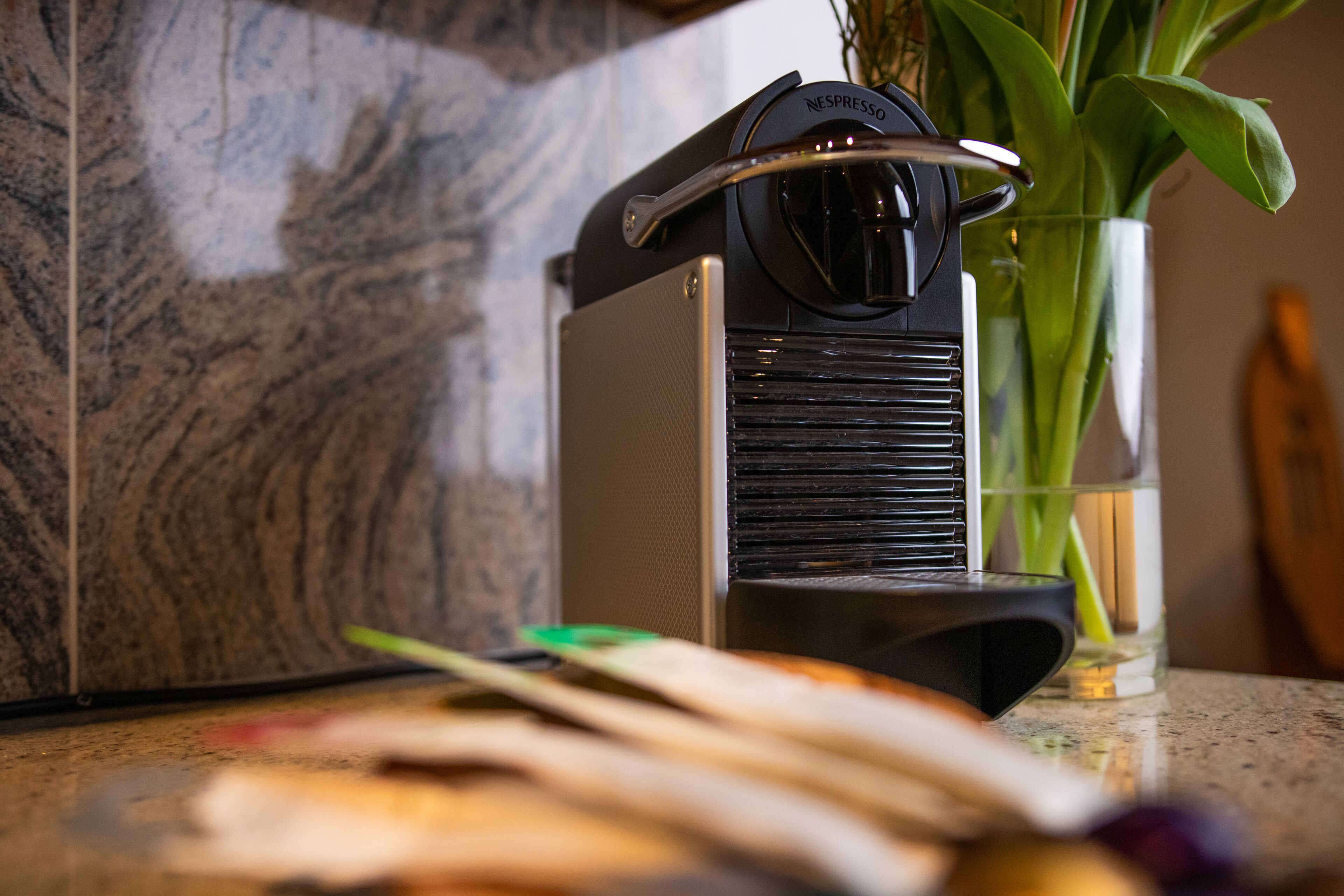 A Nespresso coffee machine on a kitchen counter with a marble backsplash.