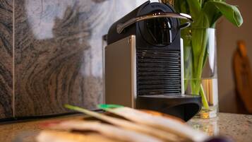 A Nespresso coffee machine on a kitchen counter with a marble backsplash.
