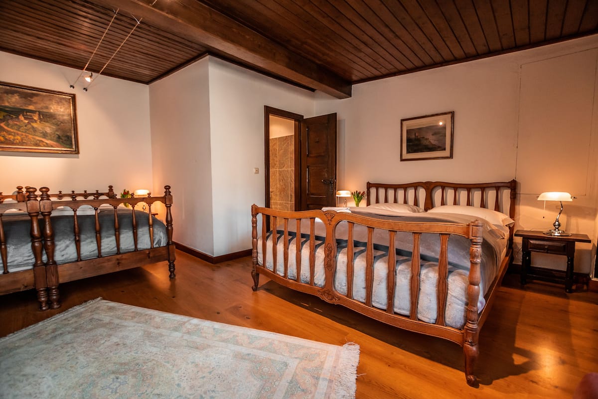 A bedroom with two wooden beds, a wooden ceiling, and a door leading to another room.