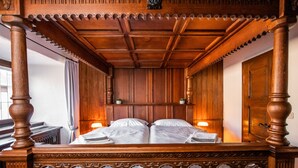 Un letto a baldacchino con struttura in legno, un comodino con una lampada e una porta in legno.