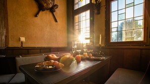 Una tavola da pranzo con cibi per la colazione, una sveglia appesa al muro e una finestra illuminata dal sole.
