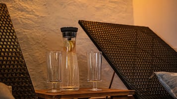 A wooden table with a bottle and two glasses, set against a textured wall.