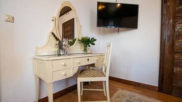 Un mobile bagno bianco con uno specchio, una televisione montata a parete e un pavimento in legno.