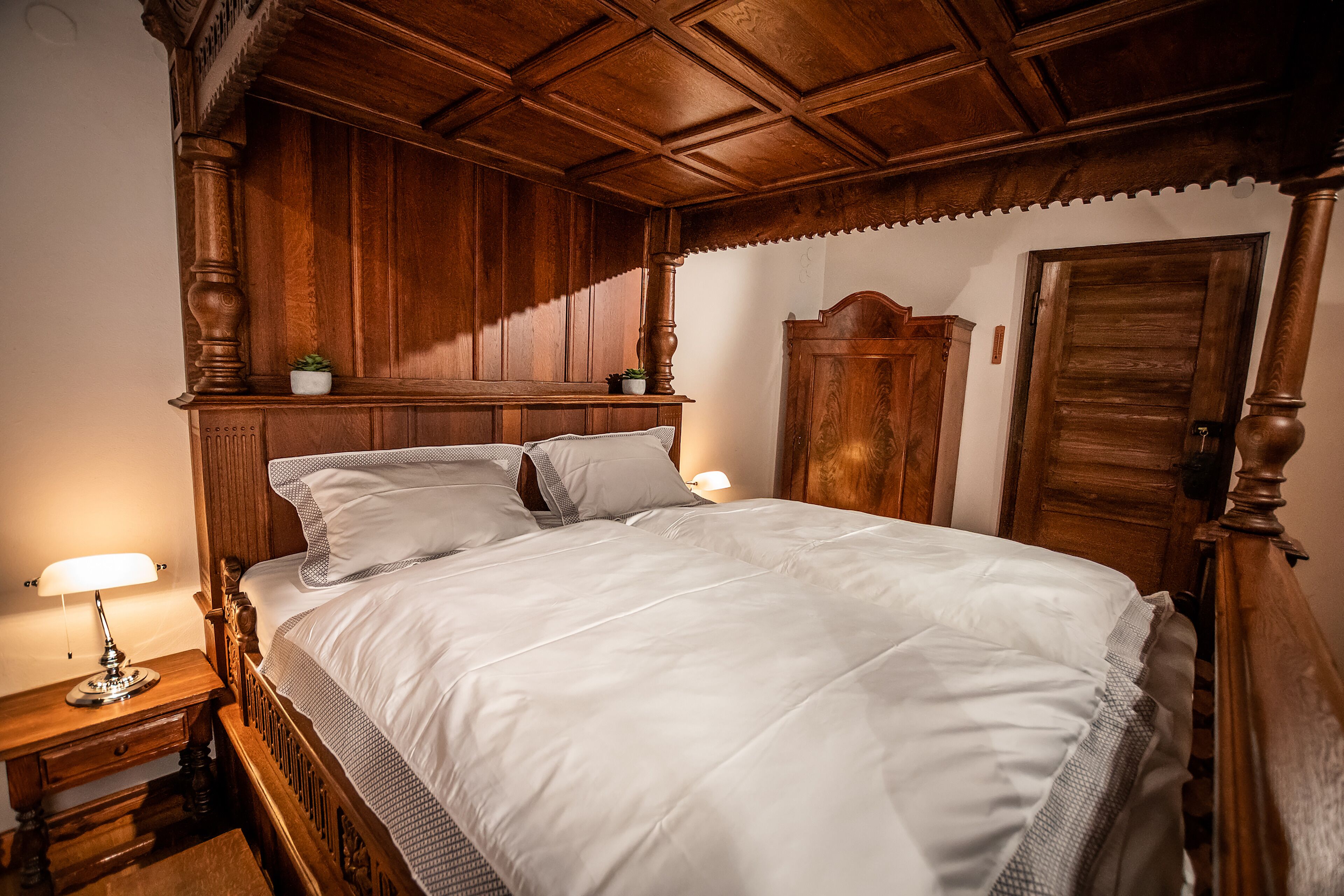 Un lit à baldaquin avec une tête de lit en bois, une literie blanche et deux lampes de chevet.