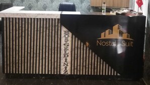 Una reception con un motivo a righe e la scritta "Nostaji Suit". Al muro dietro la reception, ci sono dei quadri con certificati.