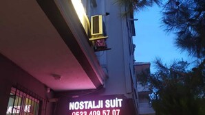 Un edificio con un neon che recita 'NOSTALJI SUIT' e un numero di telefono.