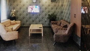Una hall moderna con pavimento in marmo, due divani, un tavolino, una TV a parete e una lampada a sospensione decorativa.