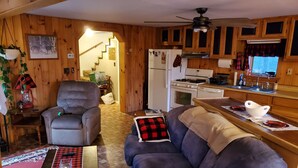 A cozy cabin interior with a living room, kitchen, and a staircase leading to a loft. - Getaway with Snowmobile, ATV, and boating access!! (Rockwood)