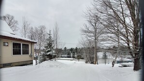A snowy residential street with houses, bare trees, and a clear sky. - Getaway with Snowmobile, ATV, and boating access!! (Rockwood)
