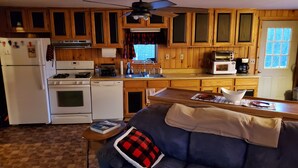 A cozy kitchen with wooden cabinets, a refrigerator, stove, and a ceiling fan. - Getaway with Snowmobile, ATV, and boating access!! (Rockwood)