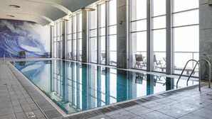 An indoor swimming pool with clear glass walls, a tiled floor, and a mural on the wall. - MIKLAT Luxury Condo & Spectacular View by FeelHome (Tel Aviv - Jaffa)
