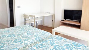 Une chambre à coucher avec un lit, un bureau, une chaise et un téléviseur.