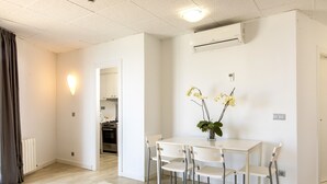 A modern living room with a white table and chairs, a small plant, and an air conditioning unit on the wall. - Flats Friends Atlantida 1 bedroom penthouse superior (Benidorm)
