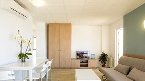 A modern living room with a sofa, a dining table with chairs, a TV, and a cabinet. - Flats Friends Atlantida 1 bedroom penthouse superior (Benidorm)