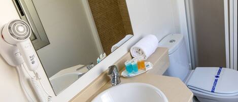 A bathroom with a white sink, a mirror, a hairdryer, a toilet, and a towel rack.
